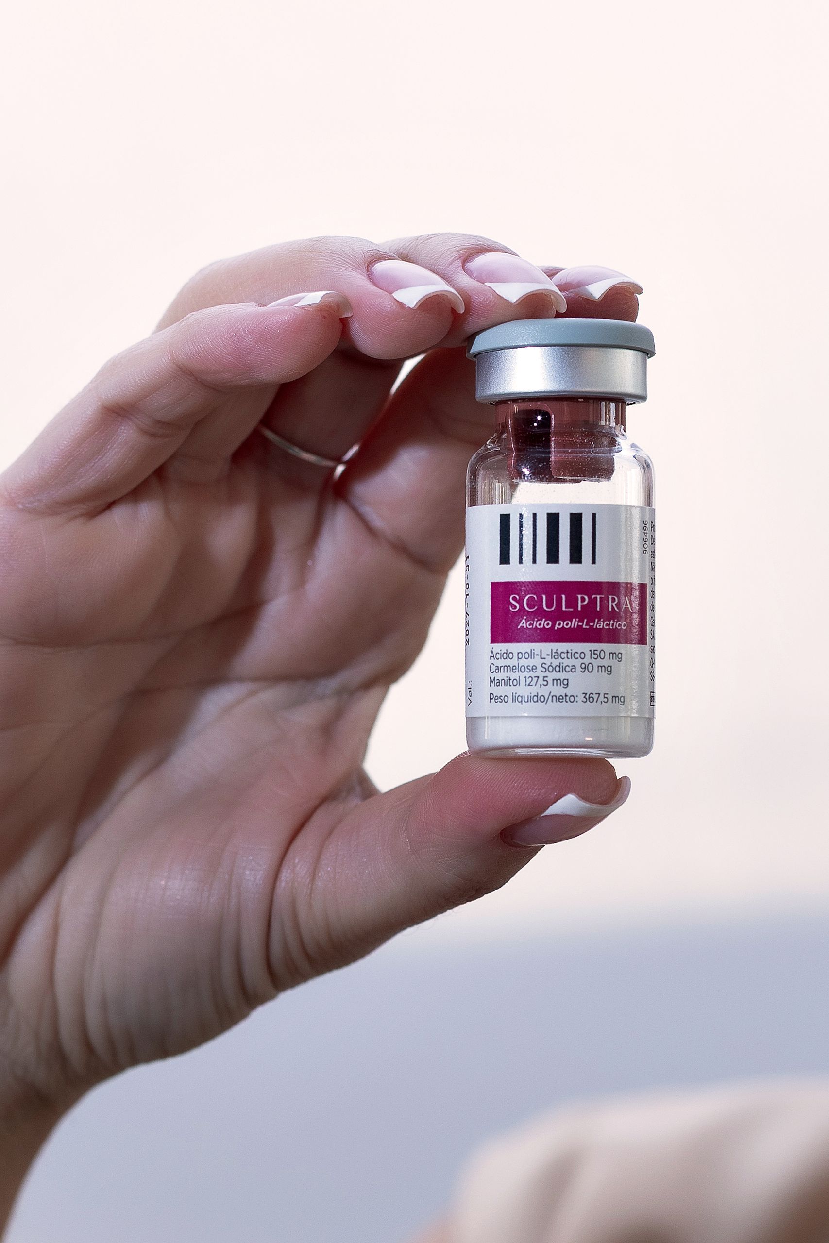 A detailed image of hands holding a Sculptra vial, showcasing product packaging.